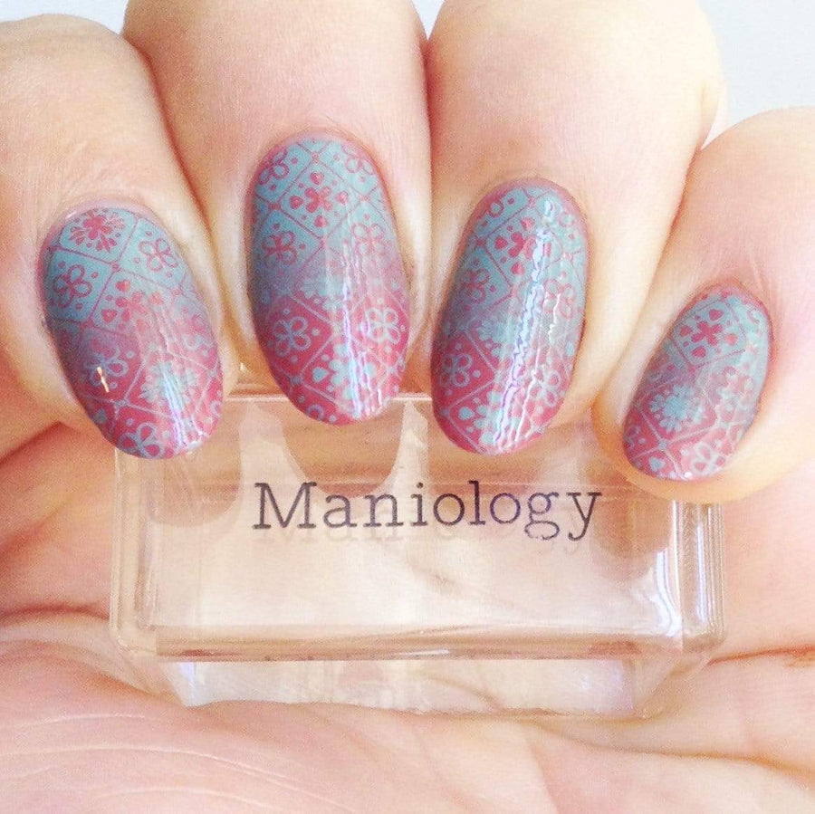  A manicured hand made with Shangri La (B296) Dusty Blue Stamping Polish holding a stamper by Maniology.