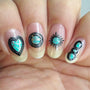 A manicured hand with heart, sun and tribal designs made with Green Stamping Polish Turquoise (B324) by Maniology.
