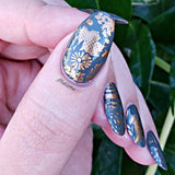 A manicured hand with Copper Orange Stamping Polish.