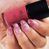  A manicured hand holding a Sugarplum (B317) rosy mauve stamping polish by Maniology.