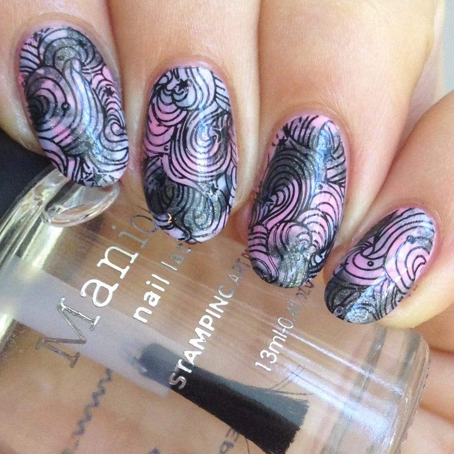 A manicured hand made with Black Magick (B293) Holographic Black Stamping Polish holding a top coat by Maniology.