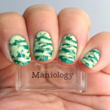 A manicured hand with camouflage design holding a stamper by Maniology (m054).