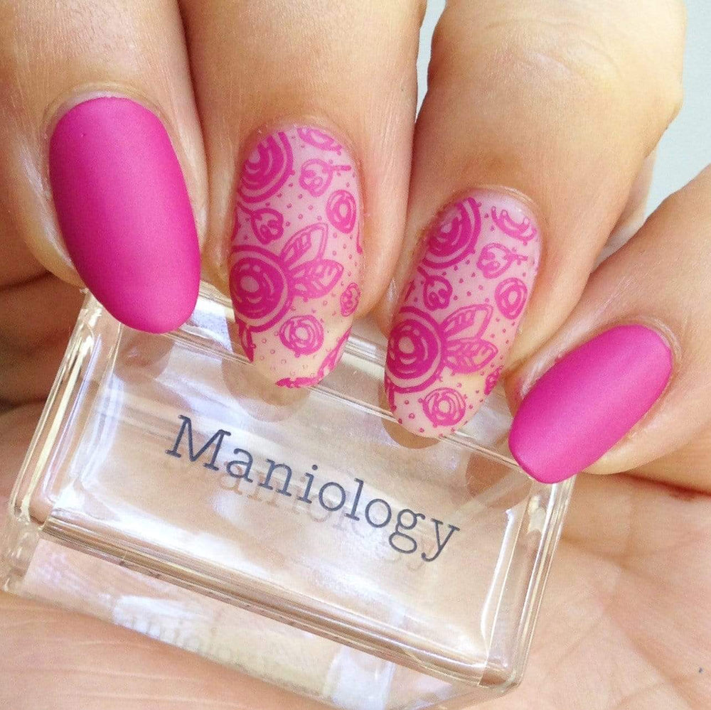 A manicured hand in pink with Bunny Hop (m048) design holding a stamper by Maniology.