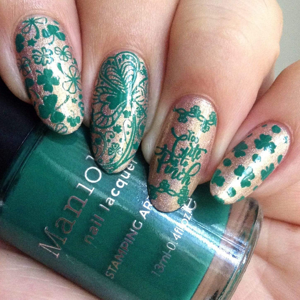 A manicured hand with clovers design holding a stamping polish by Maniology (m188).