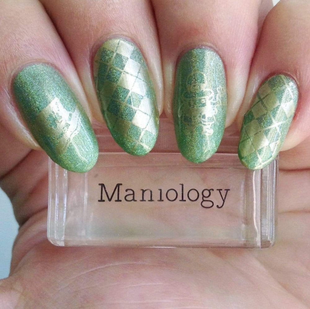 A manicured hand holding a stamper with St. Patrick's Day Lucky Charm design by Maniology (m188).