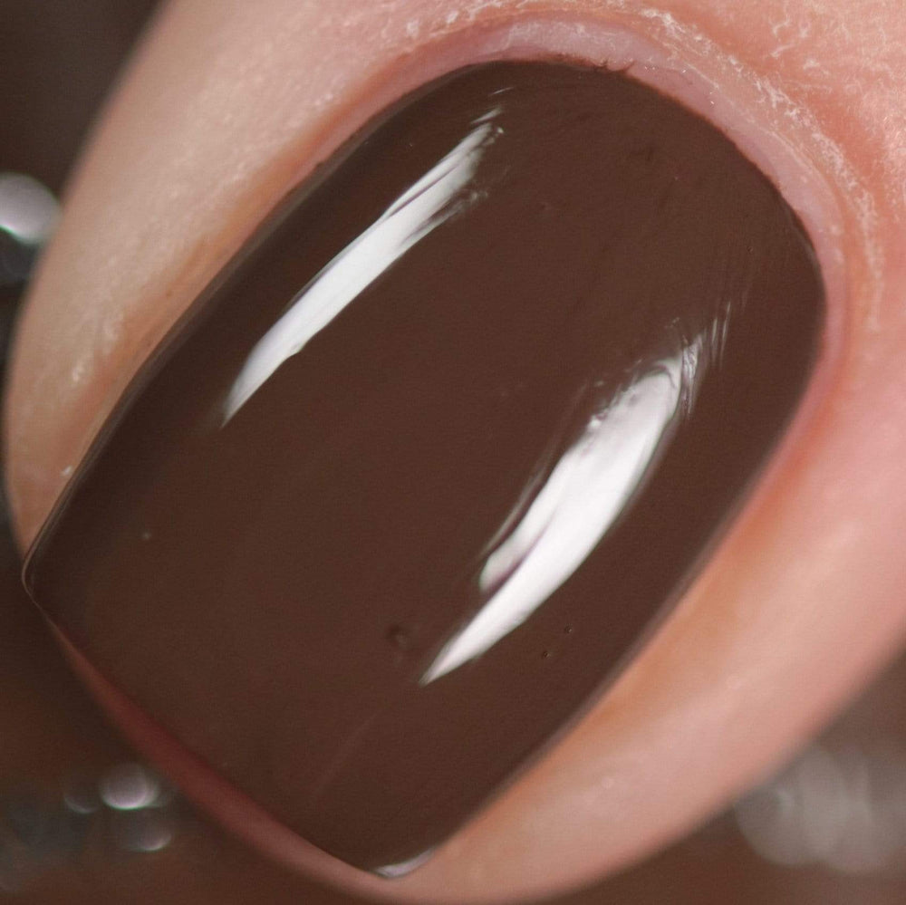 A manicured hand made with warm chocolate brown stamping polish from Sugar + Spice collection by Maniology (B351).