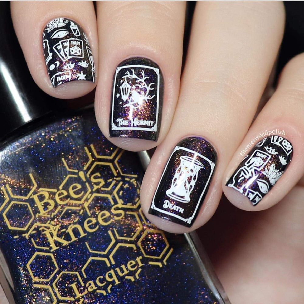A manicured hand with Supernatural: Tarot Reading designs by Maniology (m072) holding a polish.