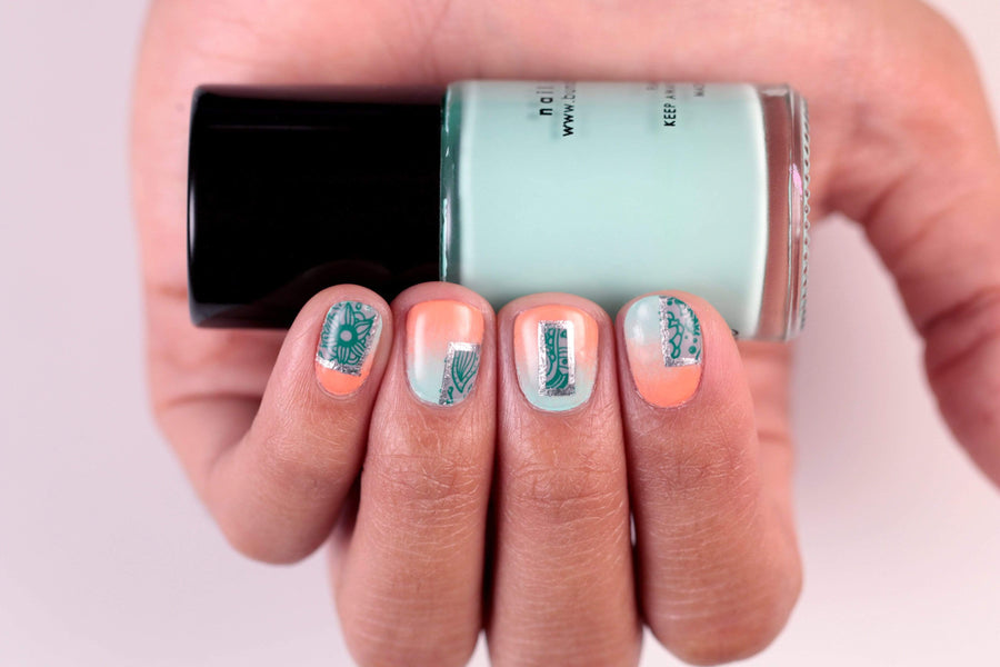 A manicured hand holding a Light Teal Stamping Polish by Maniology.