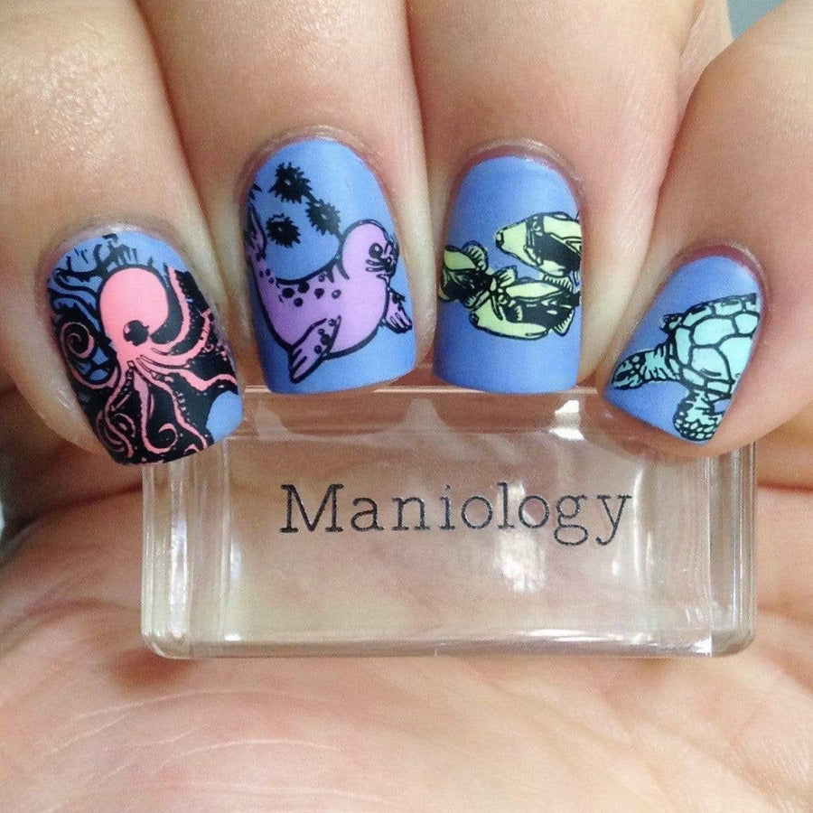 A manicured hand with seal, octopus, and fish designs holding a stamper by Maniology.