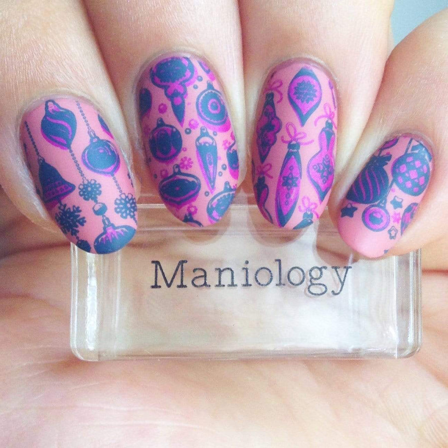 A manicured hand in pink with Winter Layers: Christmas Lights design by Maniology (m080) holding a stamper.
